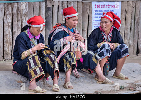 Les femmes Dzao rouge ethnique, la couture dans la rue de Ta Phin, de Lao Cai à Sapa, Vietnam, Asie Banque D'Images