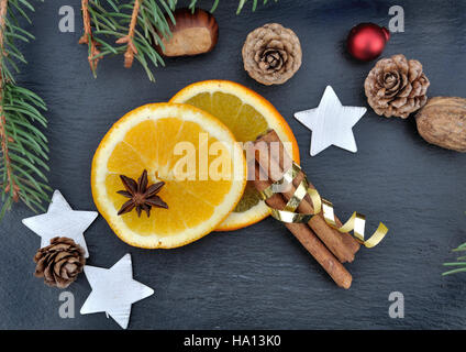 La cannelle, l'anis et les tranches d'orange parmi les décorations de Noël sur fond d'ardoise Banque D'Images