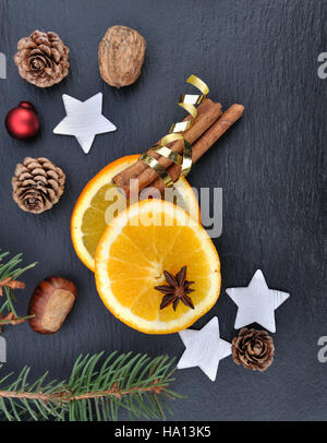 La cannelle, l'anis et les tranches d'orange parmi les décorations de Noël sur fond d'ardoise Banque D'Images