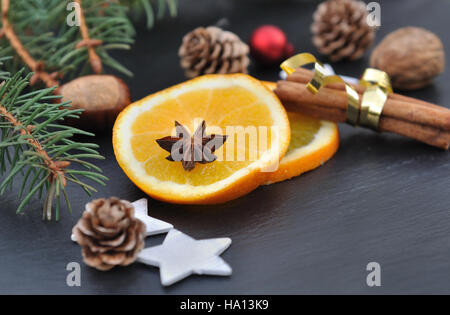 La cannelle, l'anis et les tranches d'orange parmi les décorations de Noël sur fond d'ardoise Banque D'Images