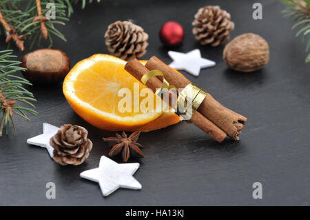 La cannelle, l'anis et les tranches d'orange parmi les décorations de Noël sur fond d'ardoise Banque D'Images