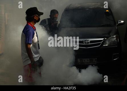 Un employé du ministère de la santé sprays anti-moustique le brouillard dans une tentative de lutte contre la dengue dans un quartier à Jakarta, Indonésie. La buée se fait dans des domaines considérés comme vulnérables les larves d'Aedes aegypti pour éradiquer le moustique Aedes aegypti principale source de transmission de la maladie. Banque D'Images