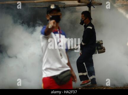 Un employé du ministère de la santé sprays anti-moustique le brouillard dans une tentative de lutte contre la dengue dans un quartier à Jakarta, Indonésie. La buée se fait dans des domaines considérés comme vulnérables les larves d'Aedes aegypti pour éradiquer le moustique Aedes aegypti principale source de transmission de la maladie. Banque D'Images