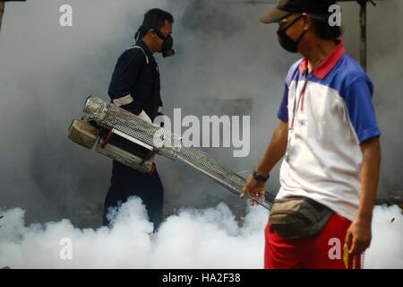 Un employé du ministère de la santé sprays anti-moustique le brouillard dans une tentative de lutte contre la dengue dans un quartier à Jakarta, Indonésie. La buée se fait dans des domaines considérés comme vulnérables les larves d'Aedes aegypti pour éradiquer le moustique Aedes aegypti principale source de transmission de la maladie. Banque D'Images