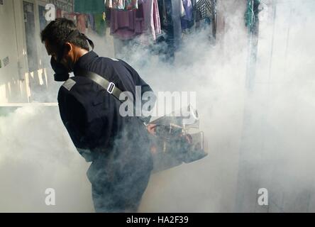 Un employé du ministère de la santé sprays anti-moustique le brouillard dans une tentative de lutte contre la dengue dans un quartier à Jakarta, Indonésie. La buée se fait dans des domaines considérés comme vulnérables les larves d'Aedes aegypti pour éradiquer le moustique Aedes aegypti principale source de transmission de la maladie. Banque D'Images