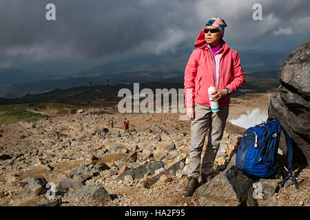 Femme en admirant la vue et de l'eau potable pendant une pause sur un sentier de randonnée dans le Parc National de Daisetsuzan, Hokkaido, Japon. Banque D'Images