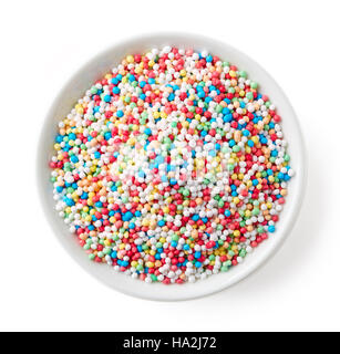 Saupoudrer bonbons colorés points dans bol blanc isolé sur fond blanc, vue du dessus Banque D'Images
