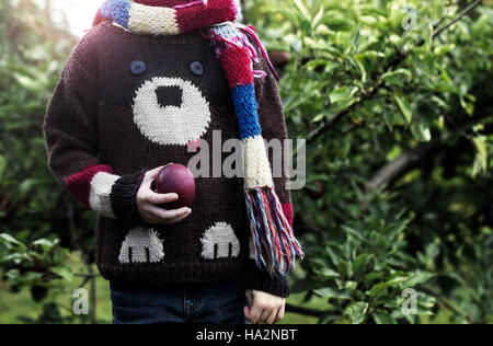 Boy standing in garden holding an apple Banque D'Images