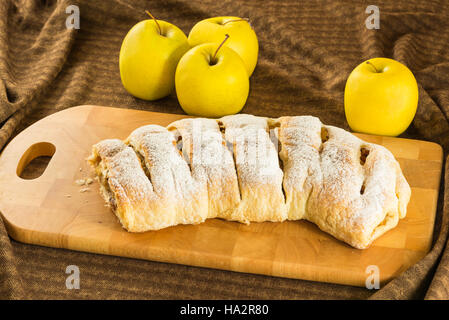 Strudel aux pommes maison (pommes Tarte) avec la pâte feuilletée, de la cannelle et raisins on a chopping board Banque D'Images