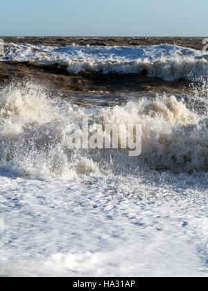 Le barattage de grandes vagues se brisant sur la rive pendant les grands vents et de pulvérisation avec de la mousse à l'avant-plan Banque D'Images