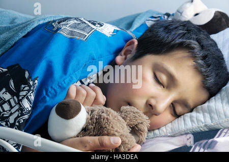 Enfant endormi dans le lit avec peluche Banque D'Images