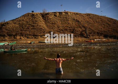 Cannon Ball, Dakota du Nord, USA. 25Th Nov, 2016. Un protecteur de l'eau ouvre ses bras comme il est dans la rivière Missouri partiellement gelé après les pouvoirs des barbelés le long de la rivière près de Oceti Sakowin Camp au Standing Rock Indian Reservation dans Cannon Ball, dans le Dakota du Nord. Du jour au lendemain, les autorités ont mis les barbelés, confisqué et détruit les canoës et protecteur de l'eau détruit un pont de fortune qui a été utilisé pour traverser la rivière la veille au cours d'une action contre l'accès du Dakota du pipeline. Crédit : Joel Angel Ju''¡Rez/ZUMA/Alamy Fil Live News Banque D'Images