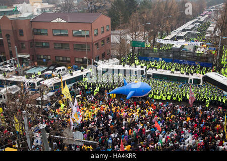 La politique de la Corée du Sud, Nov 26, 2016 : Des policiers montent la garde en tant que personnes au cours d'une manifestation appelant à la démission du Président de la Corée du Sud Park Geun-hye sur un lieu situé à 200 mètres de l'élection présidentielle Blue House à Séoul, Corée du Sud. Selon les organisateurs, à environ 1,9 millions de personnes se sont jointes à la manifestation de tout le pays le samedi comme le Parlement se prépare à attaquer le président Park après les procureurs l'ont accusée d'être complice de l'influence et de corruption liée à sa confidente de longue date Choi Soon-sil et ses secrétaires, les médias locaux ont rapporté. (Photo de Banque D'Images