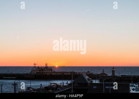 Le lever du soleil sur la mer avec le port de Ramsgate et bureaux phare sur mur du port en premier plan. Mince bande de ciel orange sur l'horizon avec lever de soleil. Banque D'Images