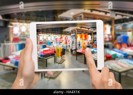 La réalité augmentée concept marketing. Hand holding digital tablet smart phone utiliser AR L'application pour vérifier les prix de vente en boutique de mode au détail mal Banque D'Images