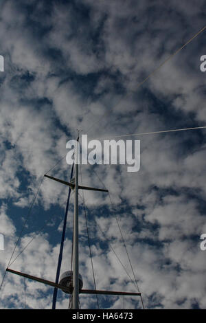 À la recherche d'un mât du yacht contre le ciel bleu avec des nuages blancs en mode portrait. Radar Radar, et l'anémomètre blipper visible. Banque D'Images