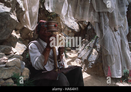 Légende : Yushu, Quinghai, Chine - juillet 2002. Un Tibétain Khampa virevoltant une prière roue comme il circumambulates la montagne au-dessus de bon augure, Thrangu Gompa Banque D'Images