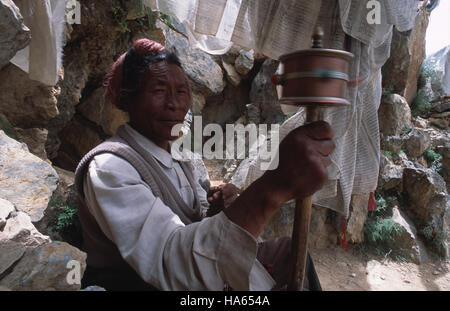 Légende : yushu, quinghai, CHINE - juillet 2002. un tibétain khampa virevoltant une prière roue comme il circumambulates la montagne au-dessus de bon augure, thrangu gompa Banque D'Images