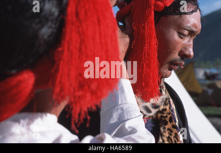 Légende : Yushu, Quinghai, Chine - juillet 2002. Les hommes Khampa la préparation de leurs bandes de cheveux rouge caractéristique avant leur danse représentation lors de l'annuel Yu Banque D'Images