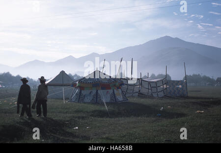 Légende : Yushu, Quinghai, Chine - juillet 2002. Deux cavaliers Khampa marche chez les tentes au Festival annuel de courses de Yushu dans l'ancien est de Tibe Banque D'Images