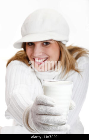 Jeune femme dans un chandail à col roulé blanc avec bonnet de laine tenant un verre de lait Banque D'Images