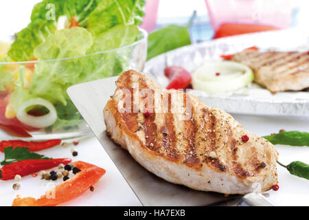 Steak de porc sur une spatule, salade mélangée dans un bol en verre Banque D'Images