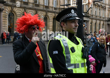 Les artistes interprètes ou exécutants d'un se tient derrière un agent de police au cours de la médiévale Style Mile à thème Carnaval à Glasgow. Banque D'Images