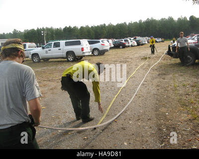 Les membres de l'équipe du NCCC AmeriCorps participent à un effort de conservation, en enroulant des tuyaux pendant la gestion des feux de forêt dans un parc national. Leur travail soutient la conservation de la nature et la protection de l'environnement dans les zones du National Park Service (NPS) des États-Unis, en s'alignant sur les objectifs nationaux et politiques liés à la préservation des ressources naturelles. Banque D'Images