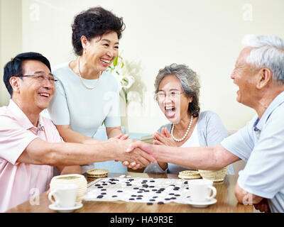 Asian men shaking hands at la fin d'un jeu weiqi. Banque D'Images