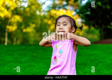 Adorable girl making faces dans le parc Banque D'Images