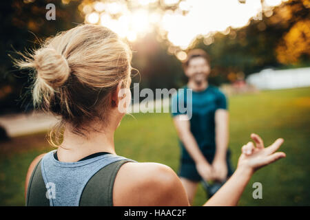 Vue arrière photo de femme à l'homme du parc l'entraînement avec kettlebell en arrière-plan. Banque D'Images