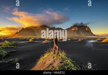 Coucher du soleil à Vestrahorn randonneur profitant de la montagne (Batman) et de sa plage de sable noir en Islande Banque D'Images