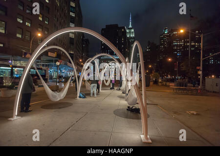 Les visiteurs de Flatiron Plaza à New York le Mardi, Novembre 22, 2016 'interagir avec Sky-Line Flatiron' créé par beaucoup d'architectes. L'installation de Noël est l'élément central de la 23e Rue du Flatiron Partenariat maison de la programmation. Les dix arcs lumineux avec des hamacs suspendus sous impliquer les visiteurs de se détendre et de contempler les merveilles architecturales du quartier, en particulier le Flatiron Building. (© Richard B. Levine) Banque D'Images