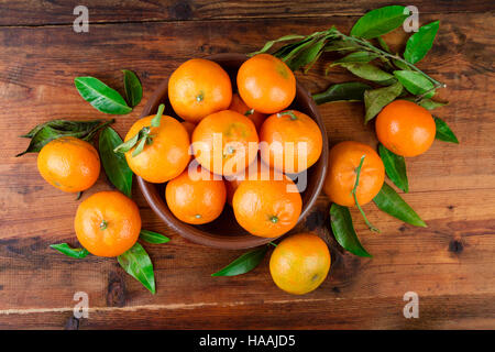 Mandarines mandarines dans un bol en céramique sur table en bois. Vue d'en haut. Banque D'Images