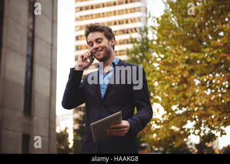 Businessman talking on mobile phone et holding digital tablet Banque D'Images