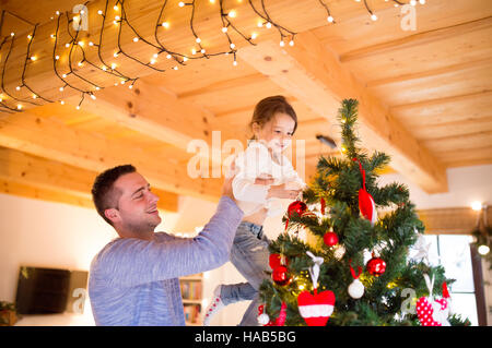 Jeune père avec daugter decorating Christmas Tree ensemble. Banque D'Images