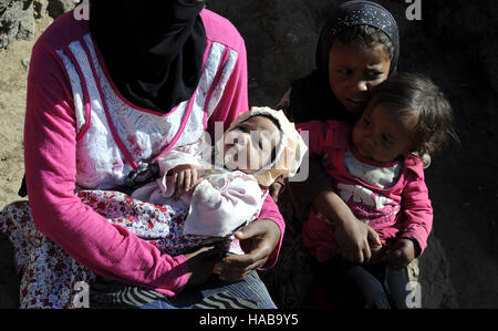 Sanaa, Yémen. 28 Nov, 2016. Une mère porte son petit fils près d'elle d'autres filles à al-Riqah camp temporaire de personnes déplacées, à 35 km de Sanaa, capitale du Yémen, après qu'ils ont fui leur maison à cause des batailles, les conflits et les frappes aériennes, le 28 novembre 2016. La guerre civile, des combats au sol et de frappes aériennes ont déjà tué plus de 10 000 personnes, dont la moitié sont des civils, blessé plus de 35 000 autres personnes et déplacé plus de trois millions, selon les agences humanitaires. © Mohammed Mohammed/Xinhua/Alamy Live News Banque D'Images