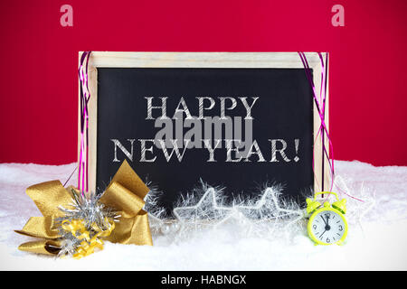 Tableau avec décoration de Noël sur fond rouge et blanc neige avec texte 'Bonne année', écrit dessus. Banque D'Images