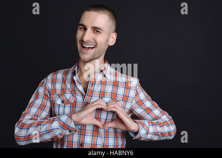 Young smiling man laissant les mains en forme de coeur Banque D'Images
