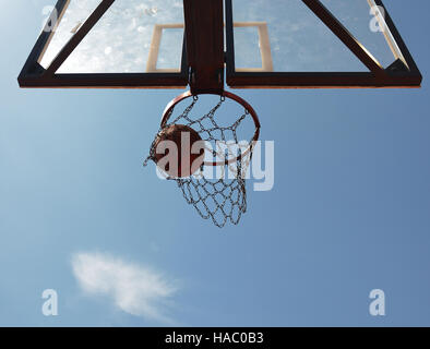 Un terrain de basket-ball à travers les swishes hoop à la recherche à partir de ci-dessous. Banque D'Images
