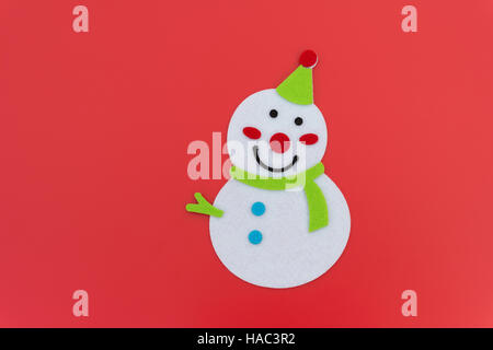 Télévision smiling toy christmas snowman avec foulard vert sur rouge Banque D'Images