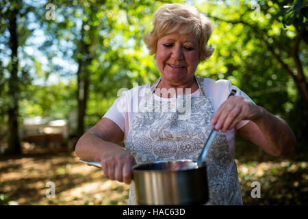 Senior woman tasting bourrage dans jardin Banque D'Images