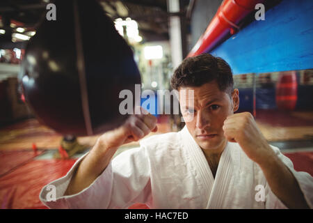 Karate fighter pratiquer le karaté avec punching bag Banque D'Images