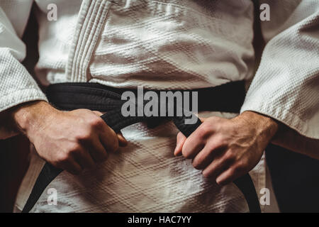 Joueur attachant sa ceinture de karaté Banque D'Images