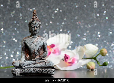 Statue de Bouddha et une orchidée fleur sur un fond brillant lumineux avec bokeh Banque D'Images