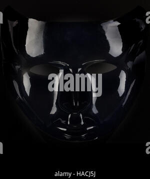 Silhouette masque noir brillant sur fond noir. Banque D'Images
