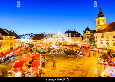 Sibiu, Roumanie. Nuit libre avec des touristes à Marché de Noël en grand marché de la ville médiévale de Sibiu, Transylvanie monument. Banque D'Images