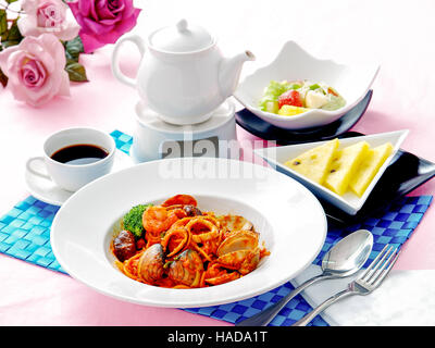 Spaghetti de fruits de mer sur plaque blanche avec salade, fruits et thé Banque D'Images