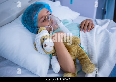 Patient avec masque à oxygène détente sur lit dans Ward Banque D'Images