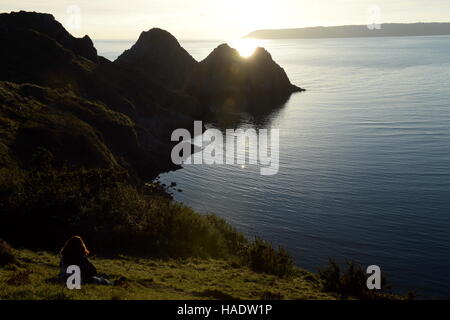 Trois falaises bay, Gower, le Pays de Galles au coucher du soleil . Une marée haute remplit la vallée avec la lumière se reflétant le Ciel clair Ciel du soir. Banque D'Images